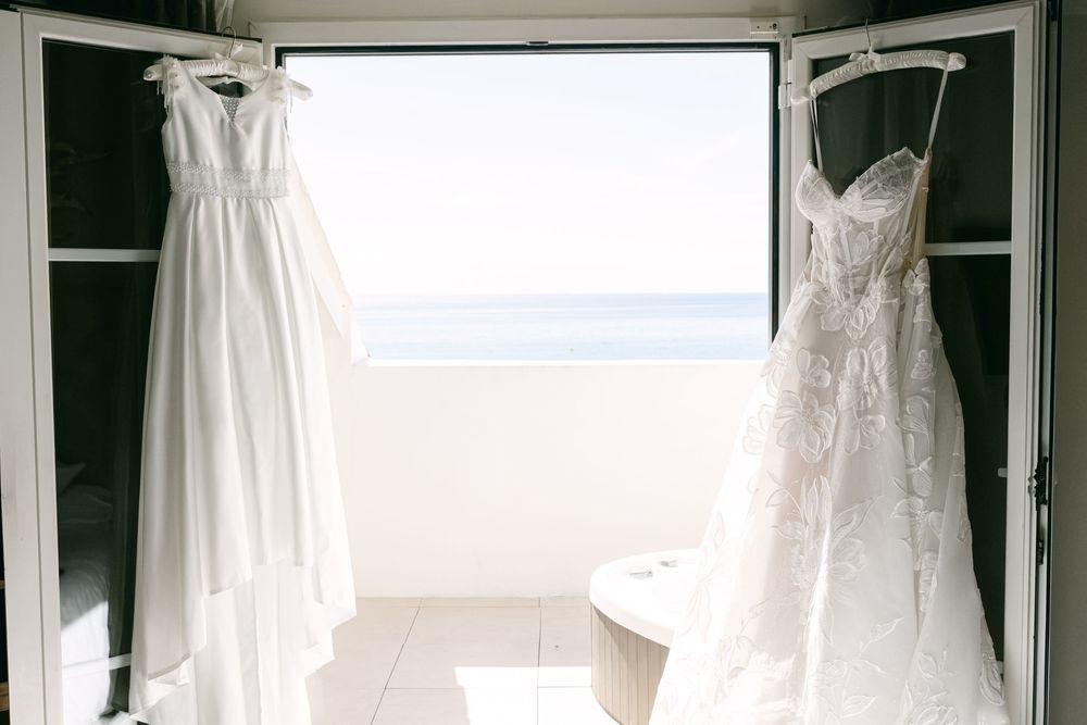 A row of white wedding dresses hanging on display in a bridal boutique with natural lighting streaming through.