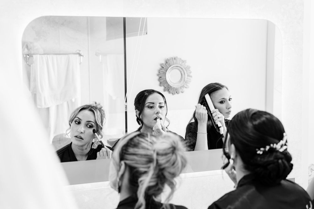 Black and white reflection in mirror shows wedding preparation scene with elegant styling and decorative details.