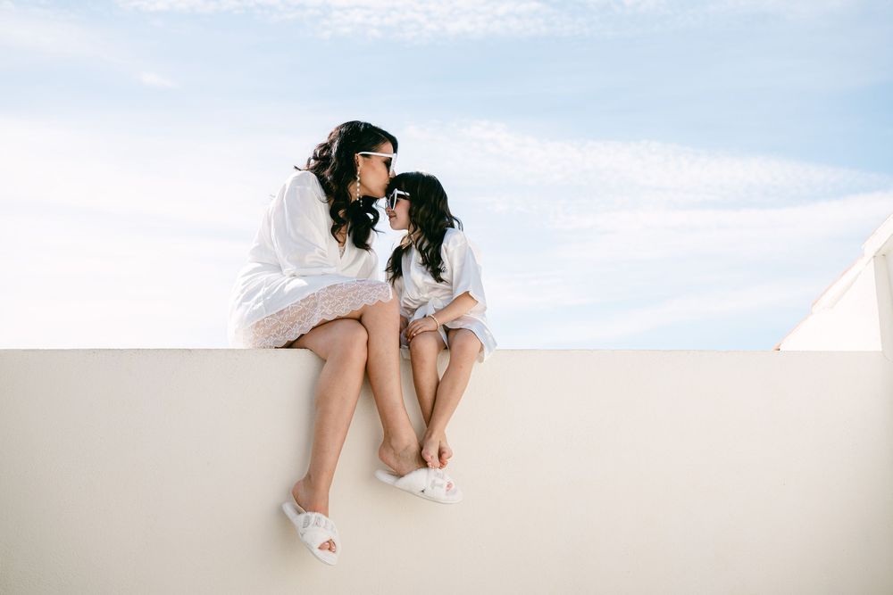 A figure in white sits on a ledge against a bright background creating a minimalist artistic composition.