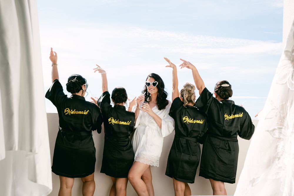 A group of people in matching black robes stand together holding bouquets in a bridal boutique.