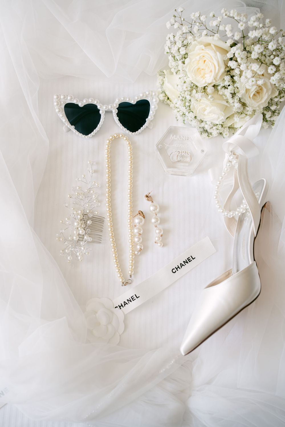 White Chanel sunglasses styled with delicate baby's breath flowers and cream roses on soft tulle fabric.