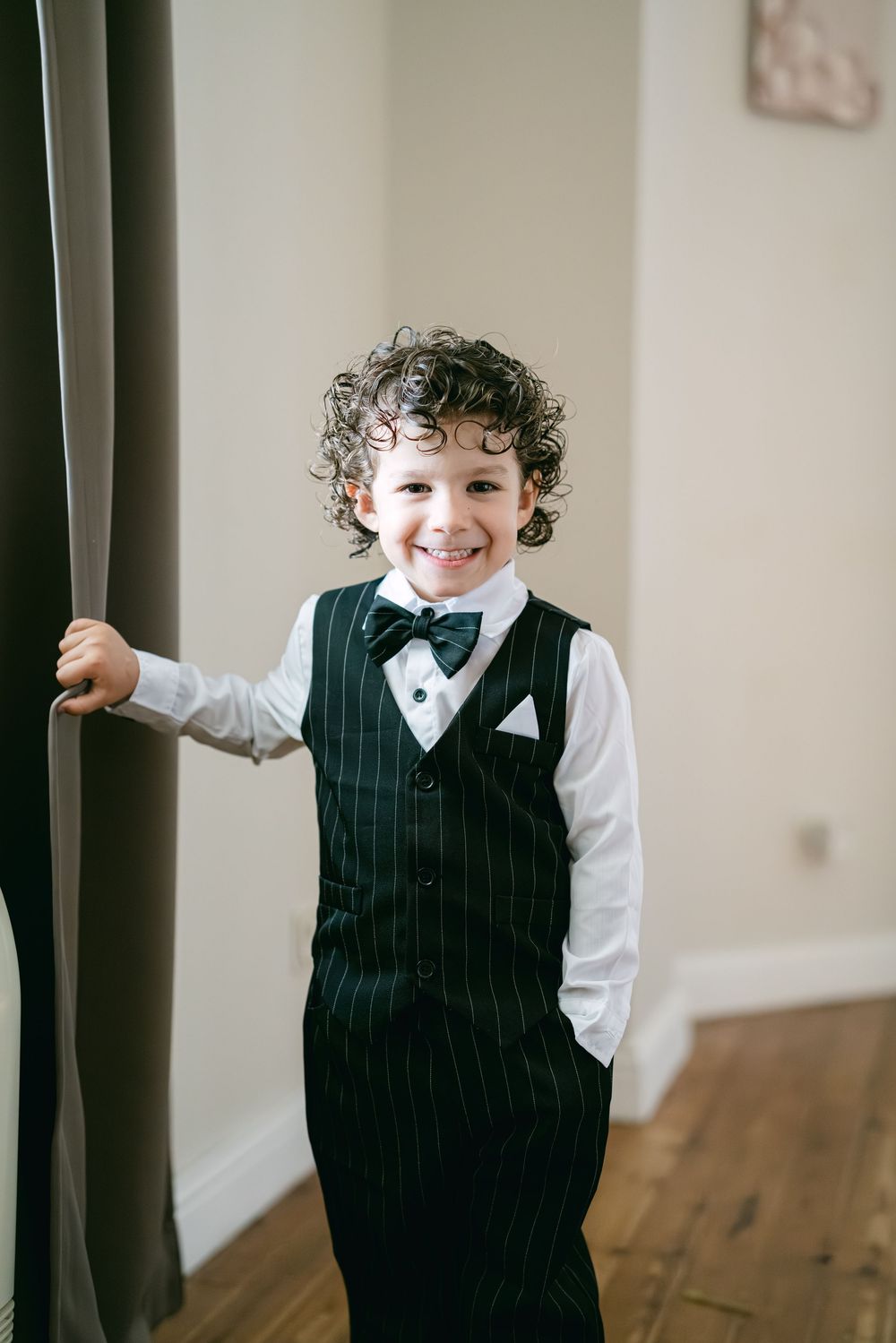 A series of photos showing a child in formal attire with pinstripes playing and posing against a wall.