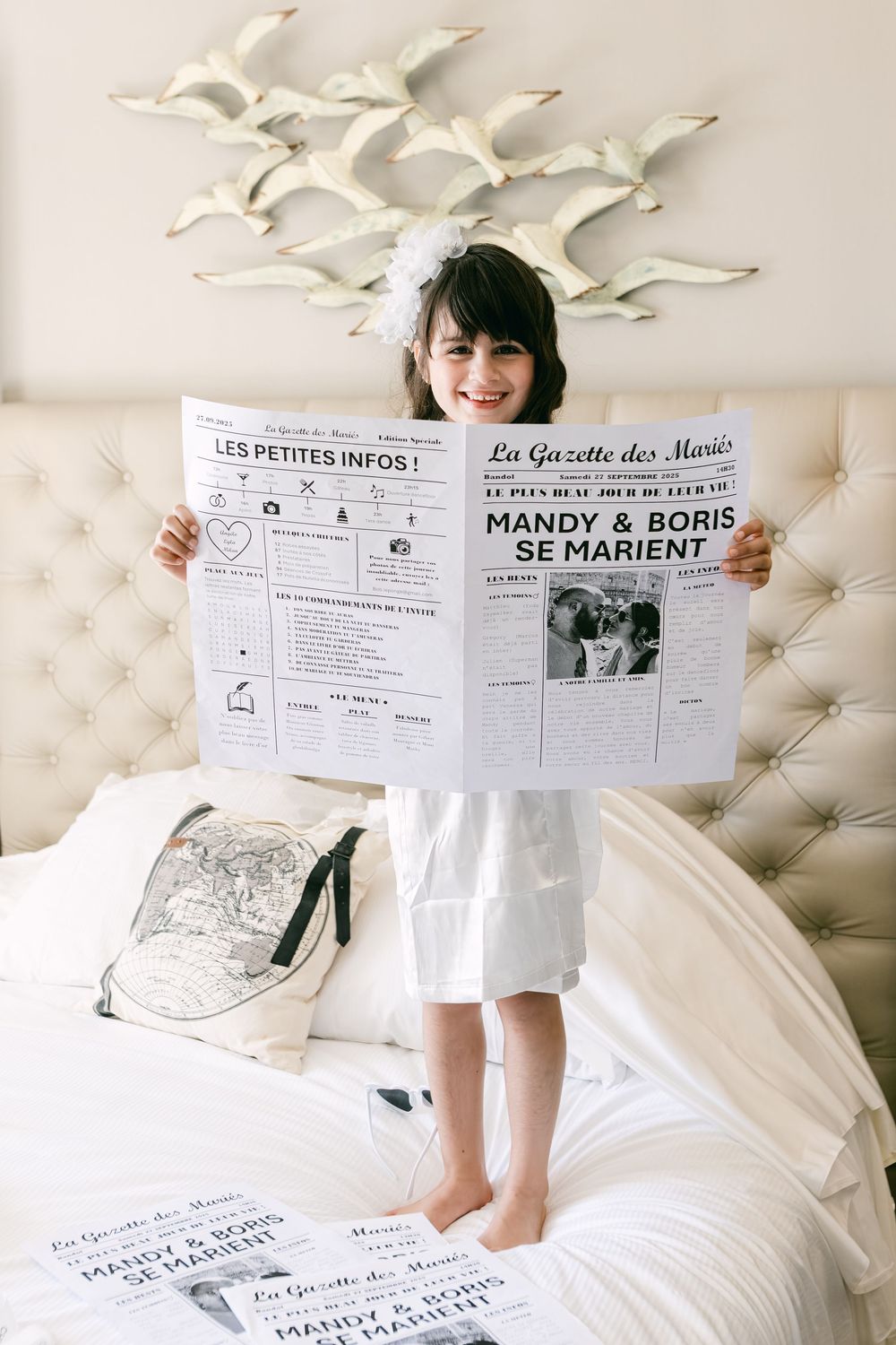 White paper wedding invitations displayed on a light tufted surface with decorative origami birds creating an elegant layout.