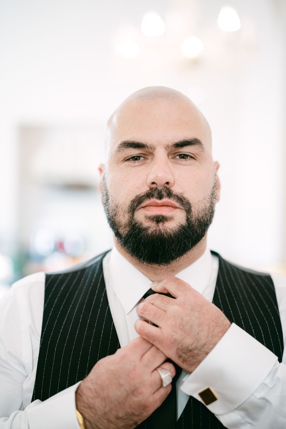 Professional portrait series showing a man in pinstripe suit adjusting his collar and beard against white background.