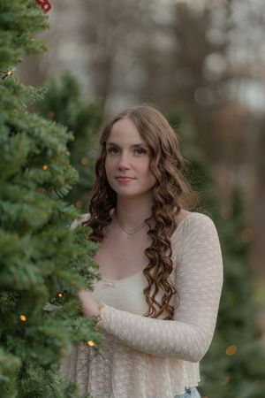 Outdoor portrait series with greenery showing someone in a white lace dress with curled hair in natural lighting.