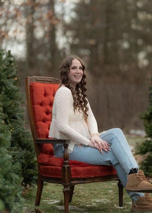 Outdoor lifestyle photo with vintage red chair and evergreen trees in a natural winter setting.