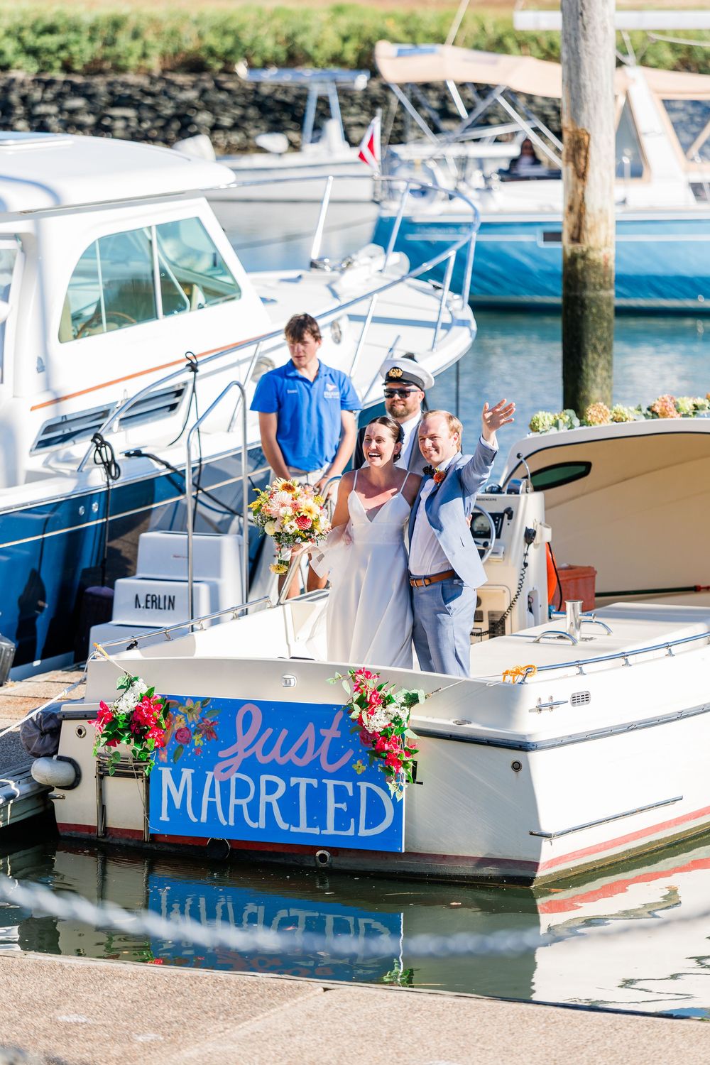 A boat decorated with 'Just Married' signage and floral arrangements docked at a marina on a sunny day.