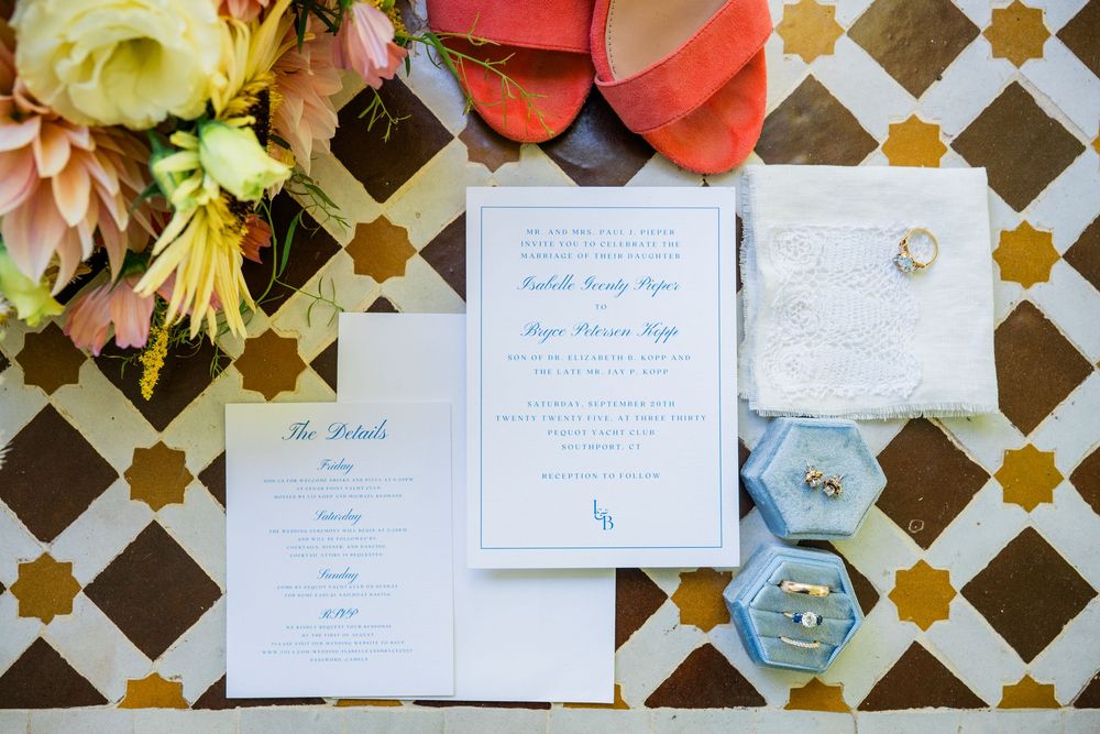Elegant wedding invitations and stationery displayed with flowers on a patterned surface.