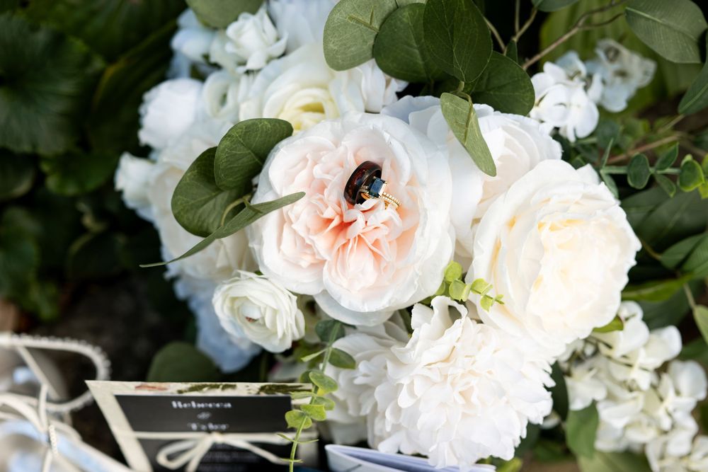 Blush garden rose with a bee surrounded by white peonies and eucalyptus in an elegant bridal bouquet.