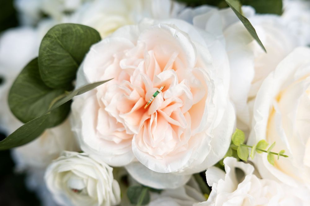 Close-up of a soft blush garden rose surrounded by white ranunculus and eucalyptus in a bridal bouquet.