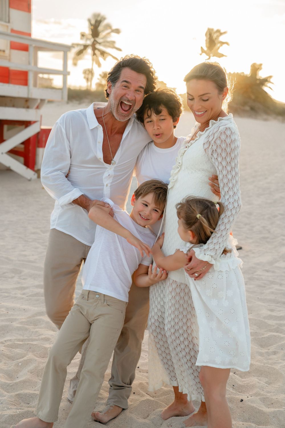 A joyful family shares candid moments together while playing on a sunny beach at sunset.