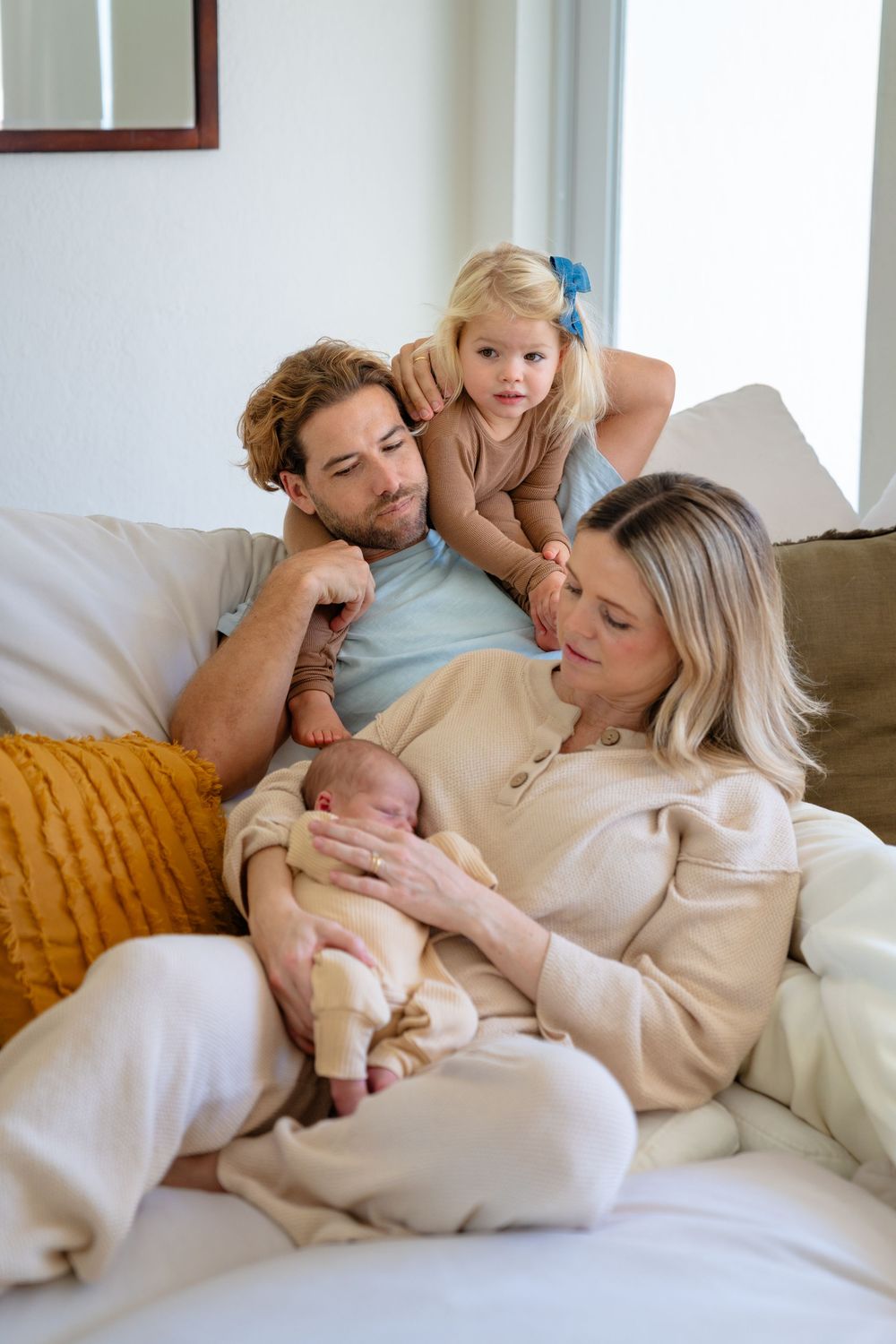 A family shares tender moments together while relaxing on a cozy couch with neutral decor.