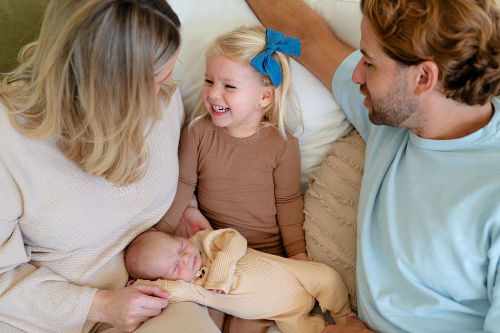 Happy family spending quality time together on a couch while sharing a sandwich.