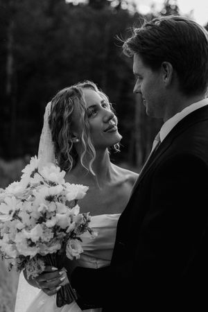 A black and white wedding portrait with the bride holding a white floral bouquet.