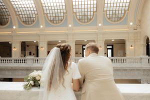 A couple shares a romantic moment under ornate architectural details and natural lighting.