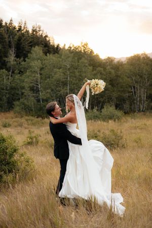 A romantic wedding photoshoot sequence in a golden field at sunset with flowing white dress and dramatic dips.