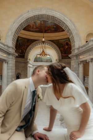 A couple dances beneath an elegant domed ceiling with classical architectural details.