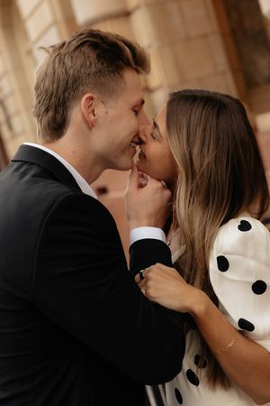 Intimate couple shares romantic moment against stone building backdrop.