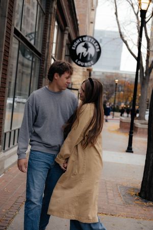 Casual couple walks together on autumn city sidewalk.