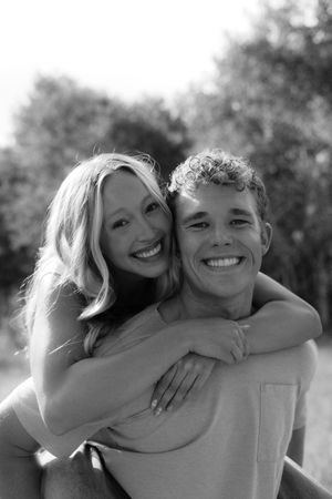 A joyful embrace captured in black and white against a natural outdoor setting.