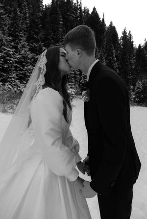 Black and white winter wedding portraits with elegant poses in a snowy forest setting.