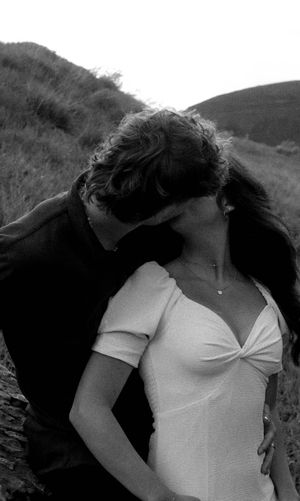 Intimate black and white portrait of a couple sharing a romantic moment outdoors.
