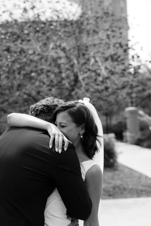Black and white photo of bride and groom sharing an emotional embrace outdoors on their wedding day.