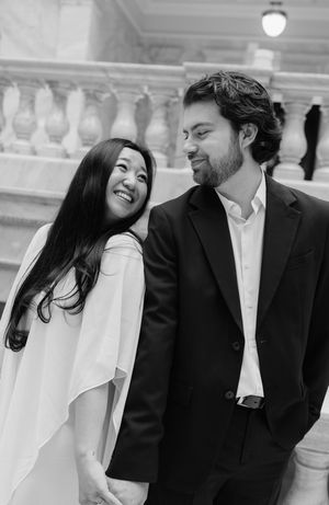 A smiling couple stands together in a formal setting.