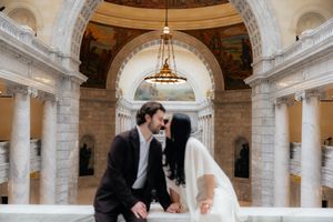 A couple posing for a wedding photograph in an ornate indoor setting.