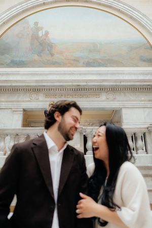 A couple embracing in front of an ornate architectural background.