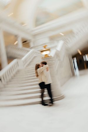 A blurred image of a couple embracing on a staircase with a warm, romantic atmosphere.