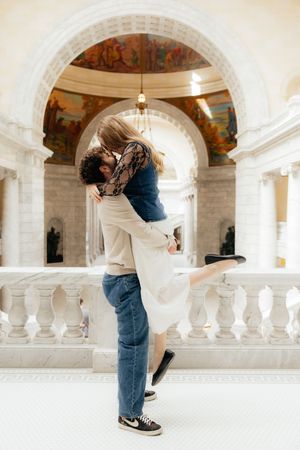 A couple embracing and kissing in a grand, ornate architectural setting.