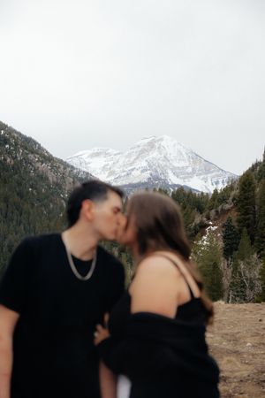 A couple embracing in front of a snowy mountain landscape.