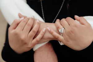 The image shows a close-up of a person's hands wearing a ring on one finger.