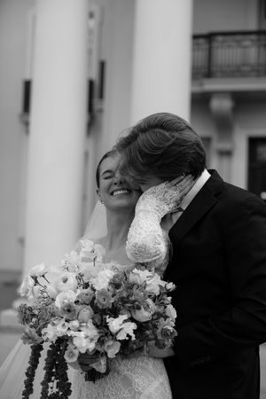 A black and white image of a smiling bride and groom embracing on their wedding day.