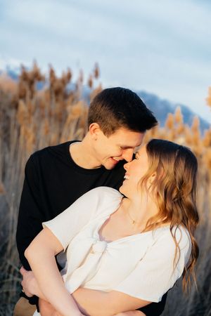 A young couple embracing and gazing lovingly at each other in a field of tall grass.