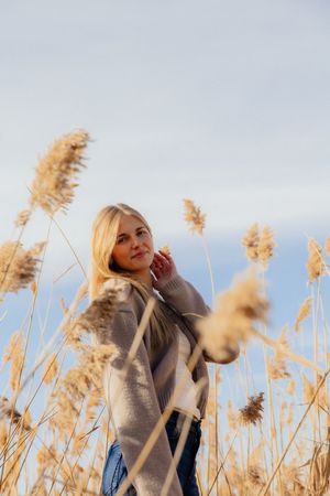A woman standing in a field of tall grass, enjoying the outdoors.