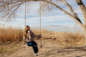 A woman swinging on a swing in a rural, natural setting.