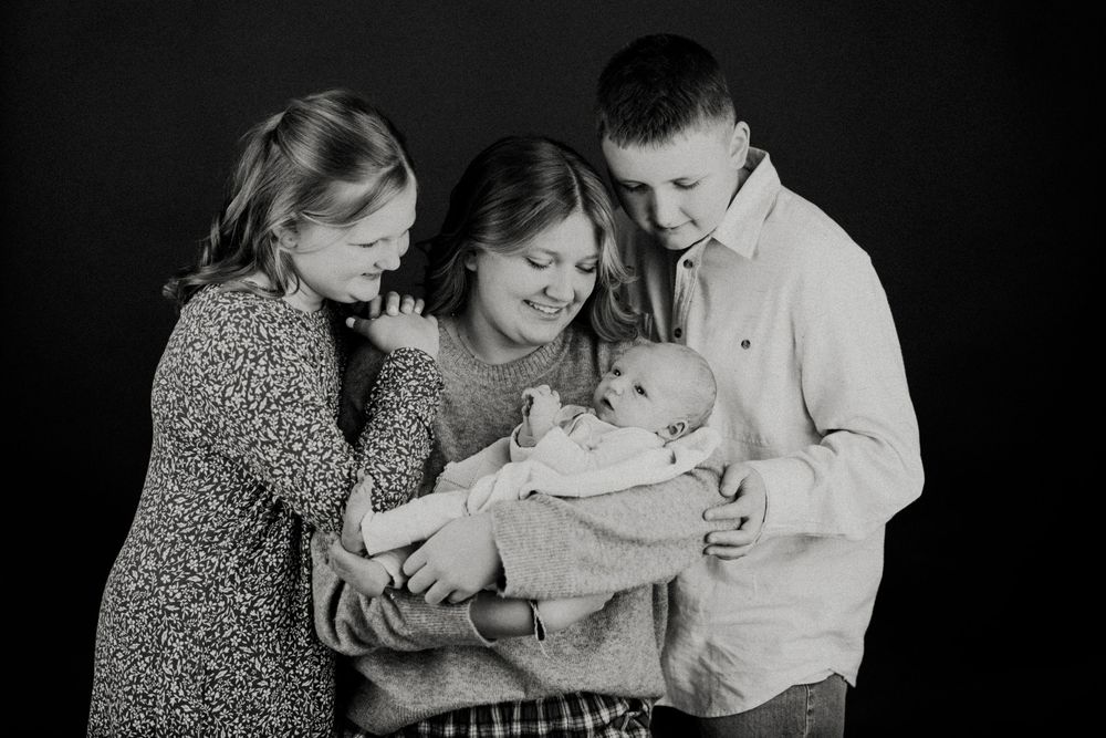 A black and white photo collage showing intimate family moments with a baby and parents in tender embraces.