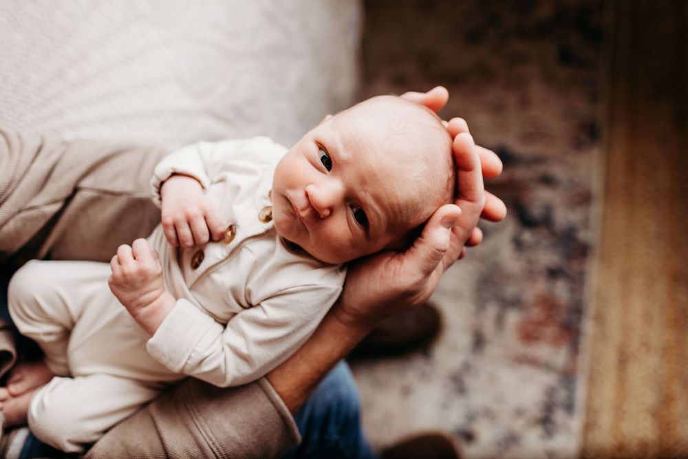 Series of candid shots showing a newborn baby in cream colored clothing against rustic backdrop.