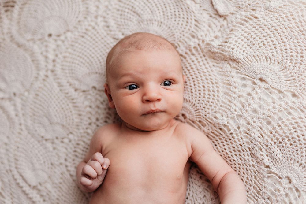 Artistic newborn photography series showing close-up details of a baby against white lace background.