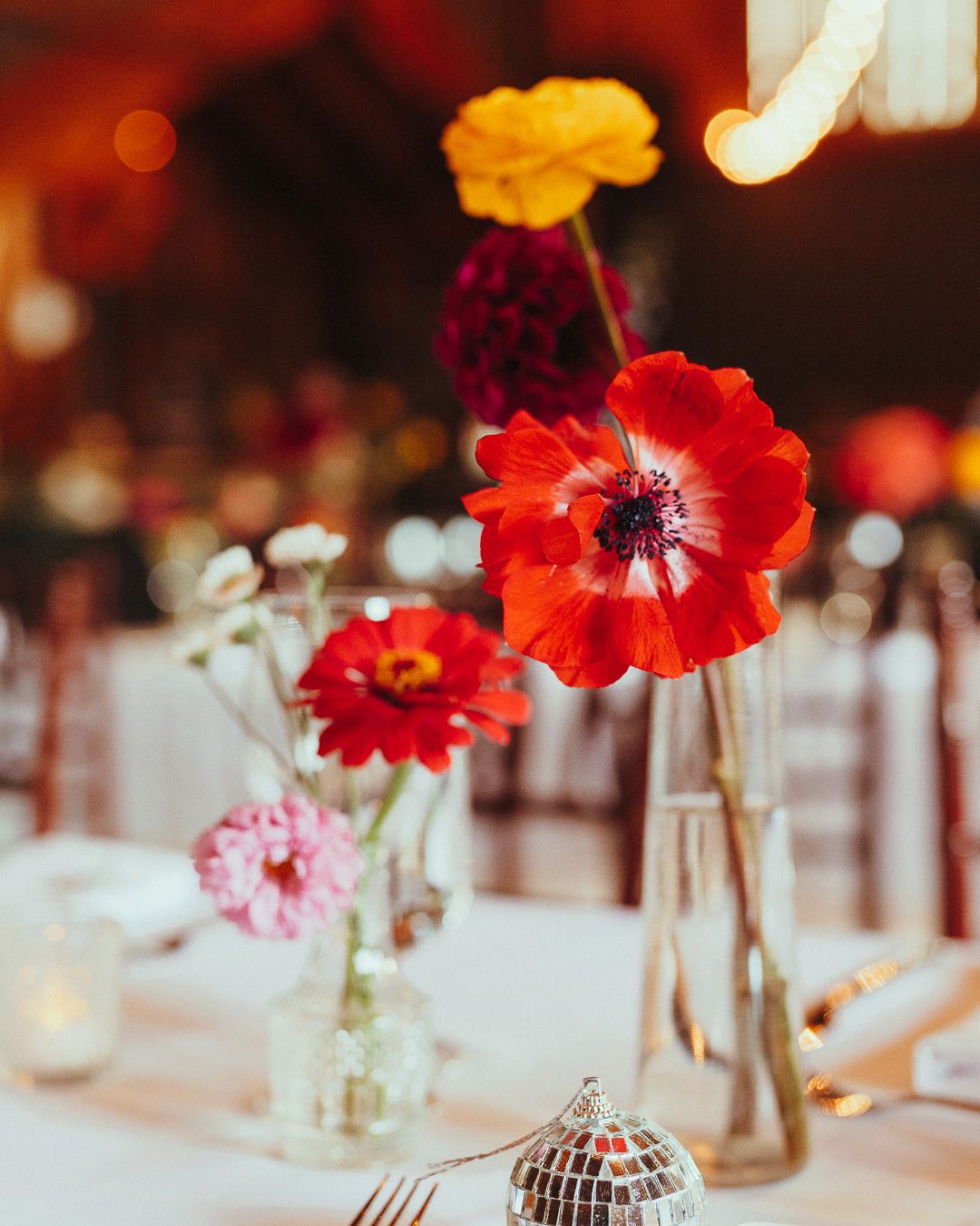 Vibrant red poppies in glass vases decorating elegant table settings.