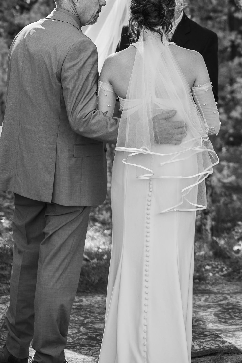 A black and white wedding photo series showing a couple in formal attire embracing outdoors.