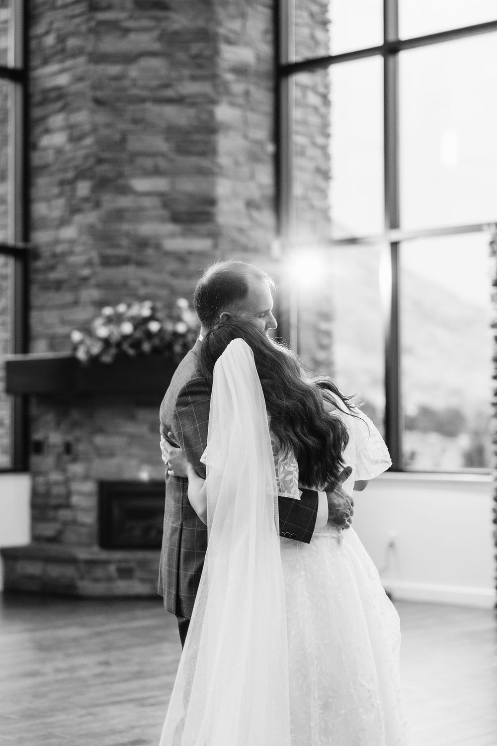 Cedar Hill Vista Romantic black and white wedding moment in front of stone wall and windows.