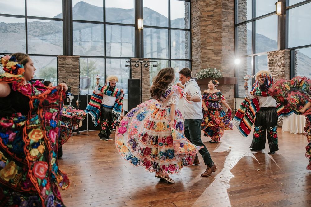 Utah Wedding celebration with guests dancing in vibrant floral dresses against mountain backdrop.
