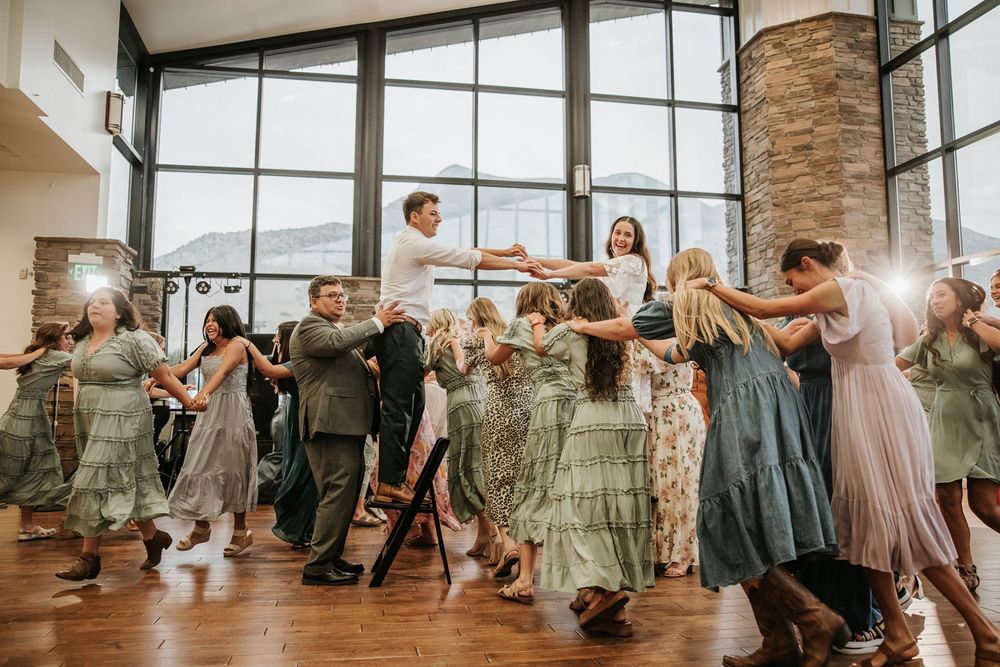 Wedding party and guests gathered in modern venue with stone walls and large windows.