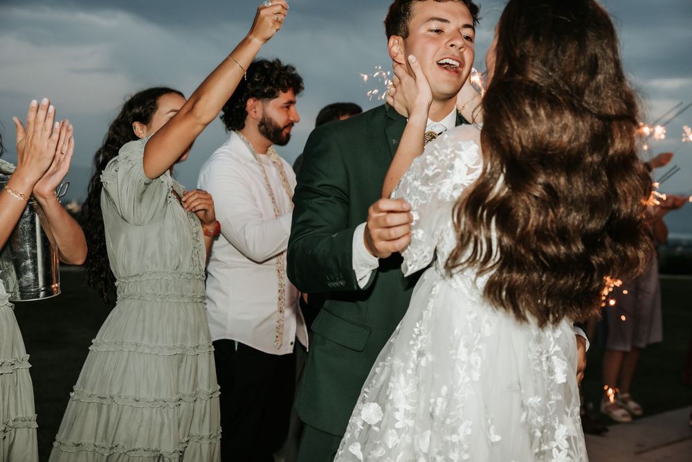 Wedding guests dancing and celebrating against dramatic cloudy sky in highland utah
