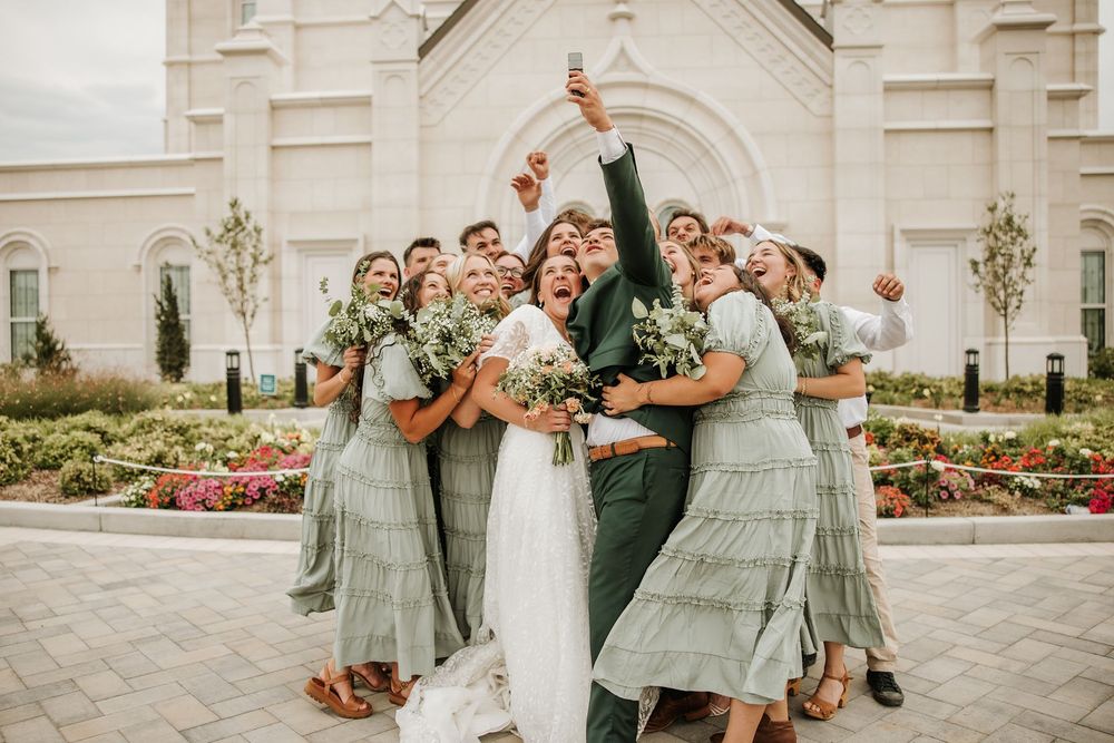 Candid Bridal party in sage green dresses celebrating with fun pose outside lds temple.