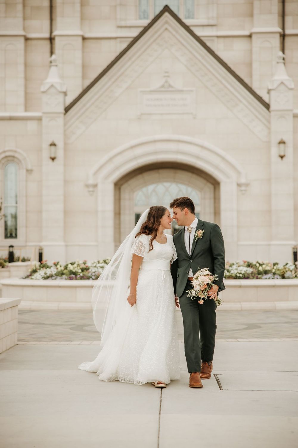 Taylorsville temple Elegant wedding portrait of couple in front of white stone church with arched doorway.