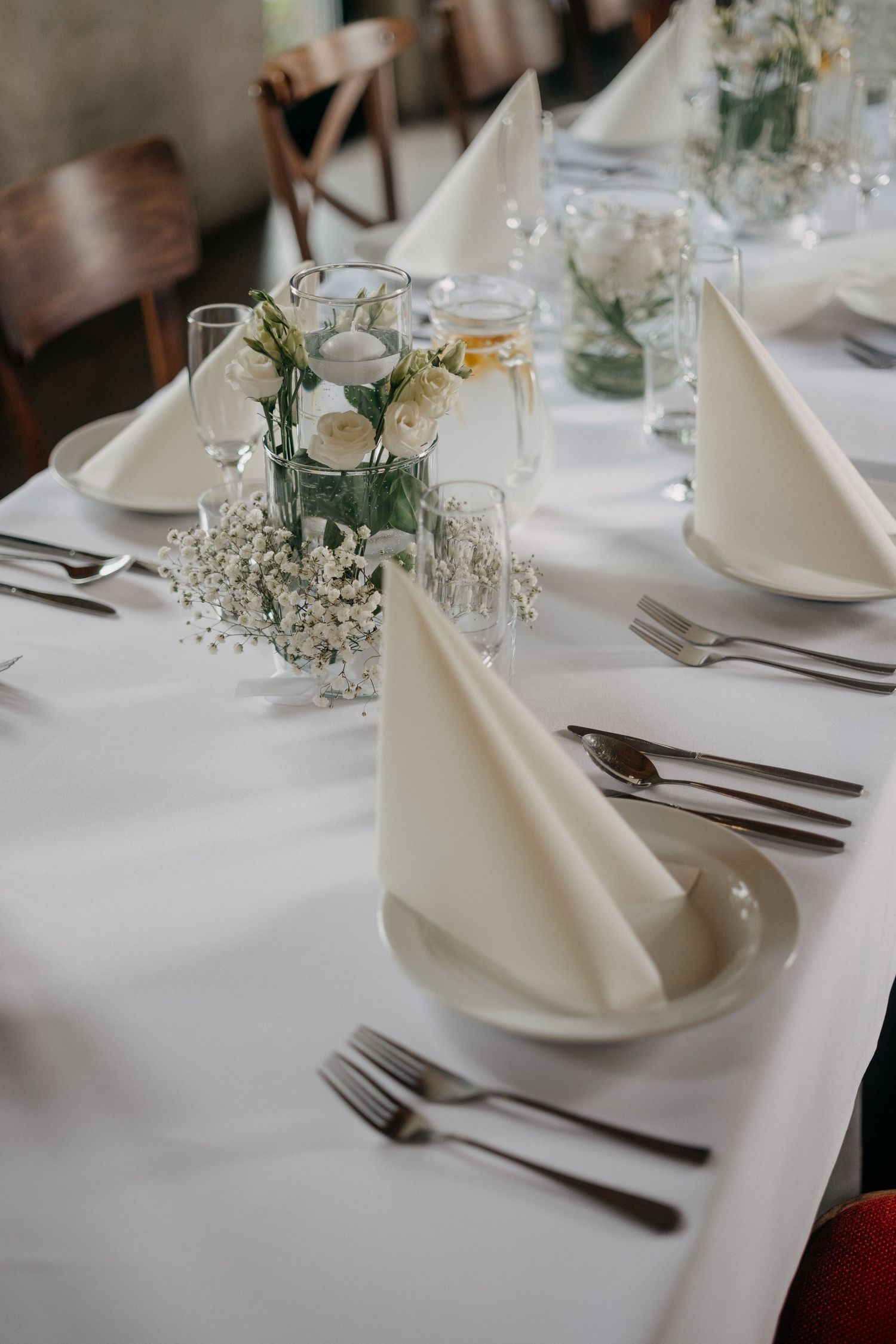 Close-up of elegant table setting with white roses centerpiece and folded napkin.
